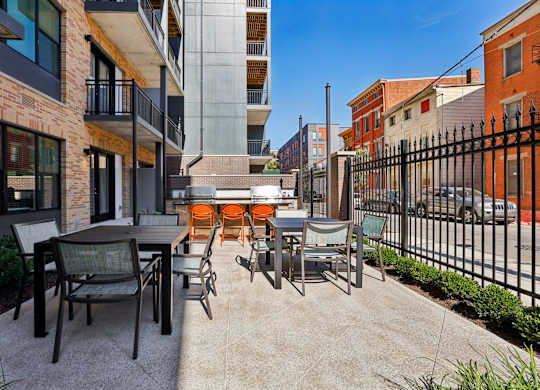 Outdoor courtyard at Contrast OTR in Cincinnati, OH with grills, dining tables, and bright orange lounge seating.