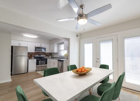 a kitchen and dining room with a white table and green chairs