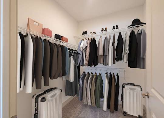 a closet with a rack of clothes and a suitcase