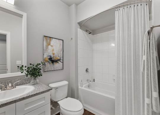 A white bathroom with a toilet, sink, and bathtub at CityWay Apartments, Indianapolis