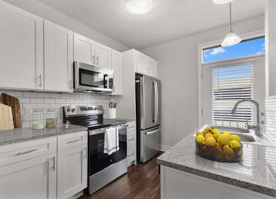 A kitchen with white cabinets and a granite countertop at CityWay Apartments, Indiana 46204