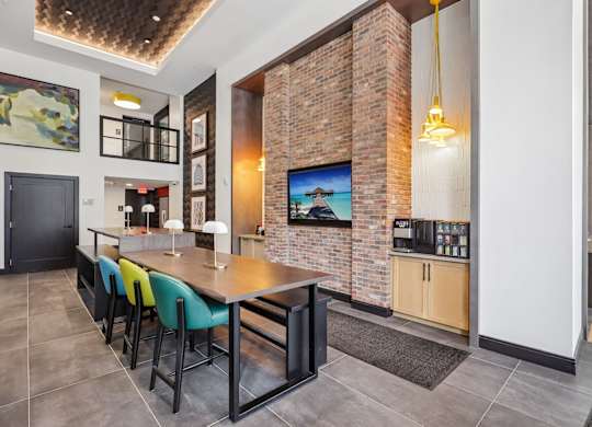 A modern kitchen with a brick wall and a long table.