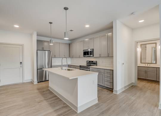 a white kitchen with a large island and stainless steel appliances