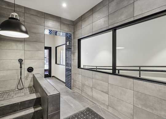 A modern bathroom with a walk-in shower and a glass door.