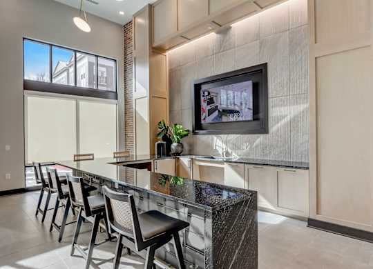 a kitchen with a bar with chairs and a tv on the wall