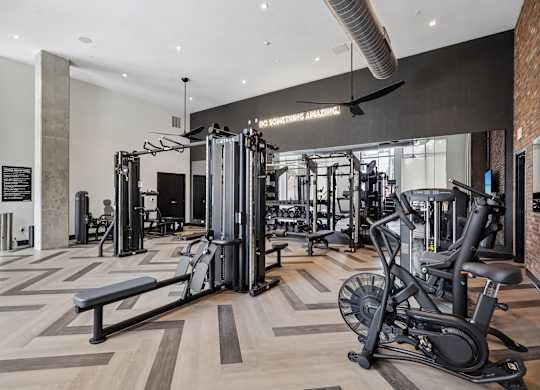 A gym with a variety of equipment including a treadmill, weights, and a bench.