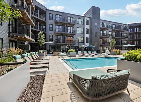 A modern poolside lounge area with a sunbed and a pool.