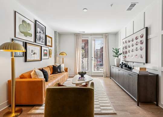 Stylish living area at Contrast OTR in Over-the-Rhine, Cincinnati featuring leather sofa, curated artwork, and natural light from French doors.