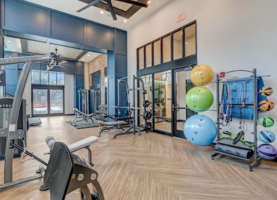 a gym with cardio equipment and weights on the floor and glass doors