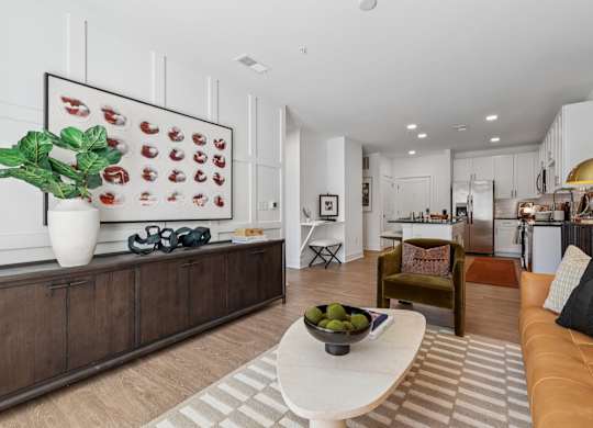 Open living and kitchen space at Contrast OTR in Cincinnati, OH showcasing designer finishes, white cabinetry, and wood-style flooring.