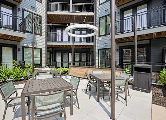 A patio with a table and chairs is surrounded by apartment buildings.