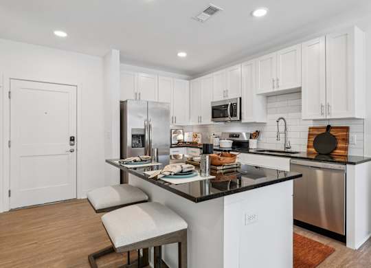 A modern kitchen with white cabinets and a black countertop.