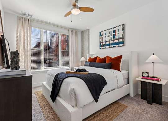 Bedroom interior at Contrast OTR apartments in Cincinnati, OH featuring bold accent pillows, urban views, and natural light.