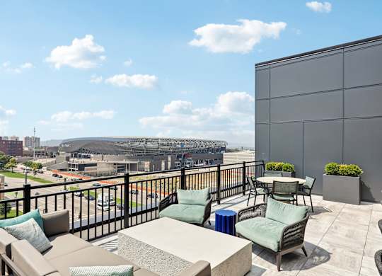A balcony with a table and chairs overlooking a parking lot and buildings.
