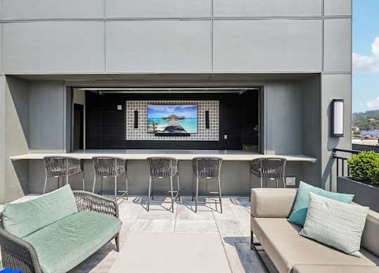 A modern outdoor seating area with a television on the wall.