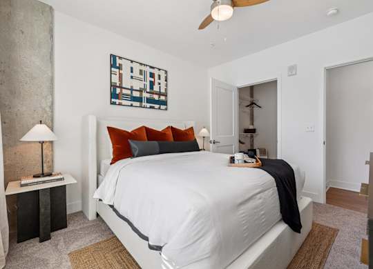 Bedroom at Contrast OTR in Cincinnati, OH with mid-century modern decor, wood nightstand, and bright window views.