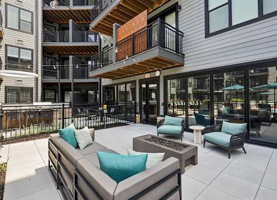 A patio with a couch and chairs is in front of a building.