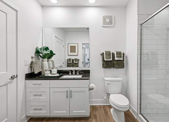 Bathroom at Contrast OTR apartments in Over-the-Rhine, Cincinnati with granite vanity, decorative accents, and full mirror.