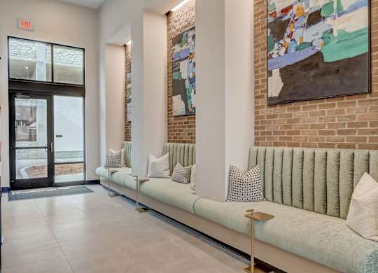 a living room with couches and a brick wall and a door