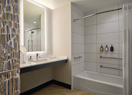 A bathroom with a white tub and a sink with a mirror.
