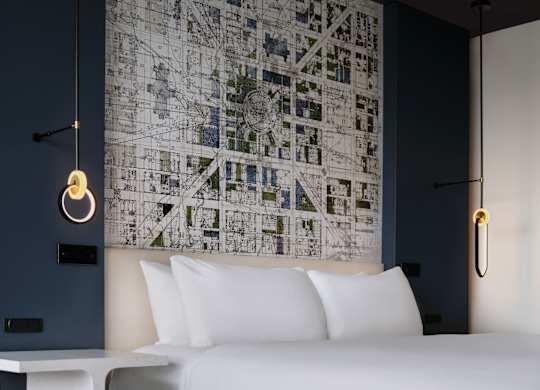 A bedroom with a large map on the wall and a bed with white pillows.