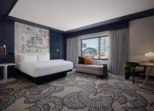 A hotel room with a large bed and a view of the city.