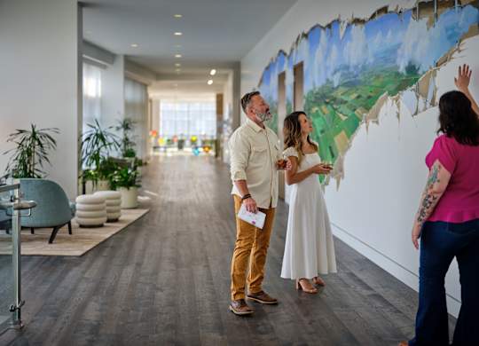 A man and woman are painting a mural on a wall.