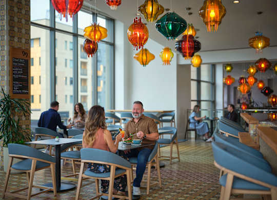 A restaurant with people dining and hanging lanterns.