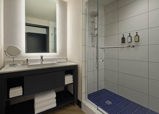 A bathroom with a sink, mirror, and shower.