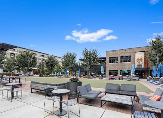 a patio area with tables and chairs and a lawn in front of a building