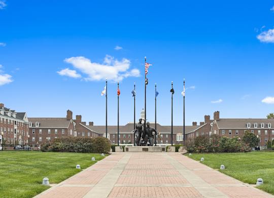 a monument in front of a building with flags and a lawn
