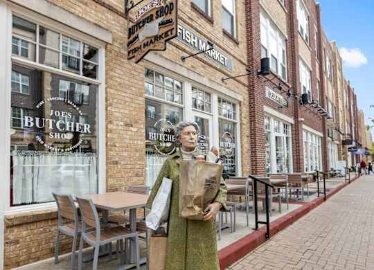 a woman standing on a sidewalk in front of a brick building