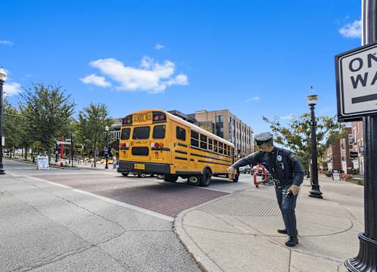 a school bus driving down a street with a man on the sidewalk