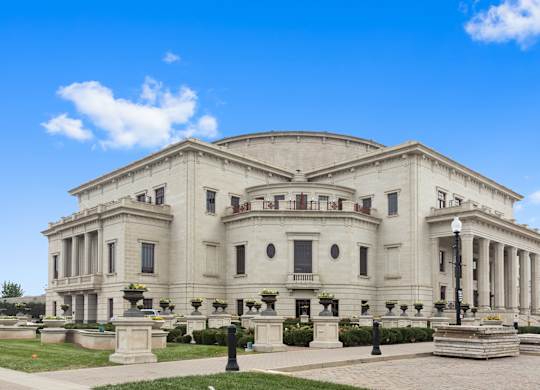 a large white building with columns and a dome with a blue sky in the background