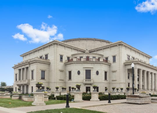a large white building with columns and a dome with a blue sky in the background