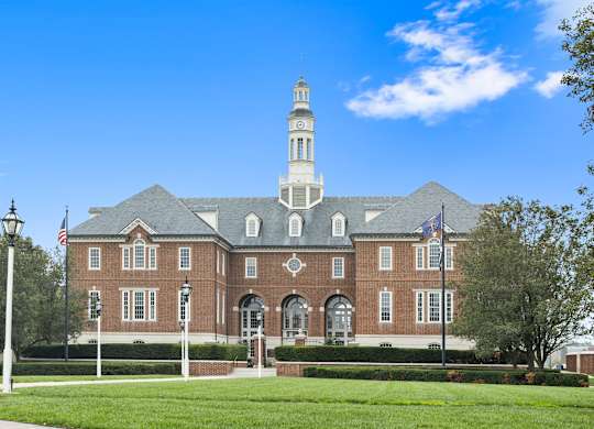 a large brick building with a clock tower on top of it at Providence at Old Meridian Apartments , Carmel, IN