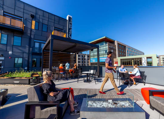 Outdoor entertainment areas in a rooftop space with grills, bar, seating, lights and art