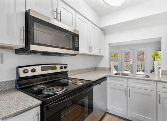 Updated kitchen at Monon Living with stainless steel appliances, granite counters, and stylish cabinetry in a pet-friendly community near the Monon Trail.