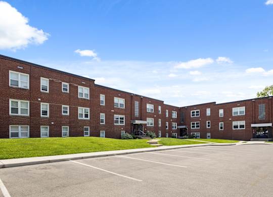 Red brick exterior of Monon Court apartments at 6131 E 61st St in Broad Ripple, Indianapolis, with adjacent parking lot