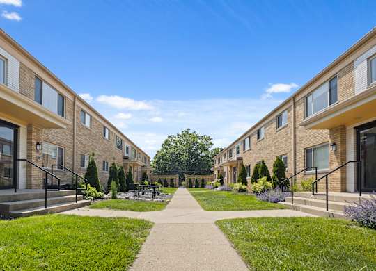 Courtyard view between mid-century style Monon Court apartment buildings featuring landscaping and sidewalk in Broad Ripple