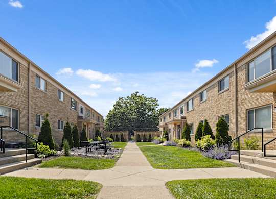 Courtyard view of Monon Court vintage apartment buildings with lush landscaping and walkways in Broad Ripple neighborhood