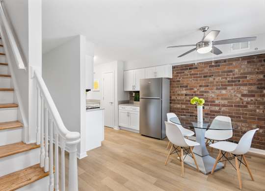 Contemporary kitchen and dining area at Monon Living in Broad Ripple featuring exposed brick, stainless steel appliances, and direct trail access via the Monon.