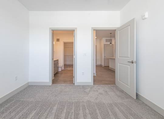 a living room with white walls and a door to a kitchen
