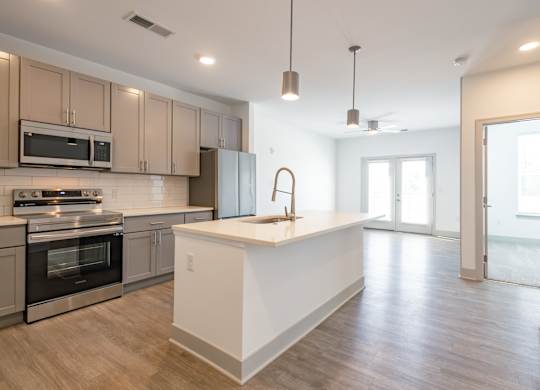 an open kitchen and living room with an island and stainless steel appliances