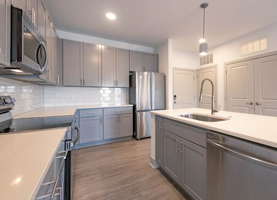 an open kitchen with stainless steel appliances and white counter tops