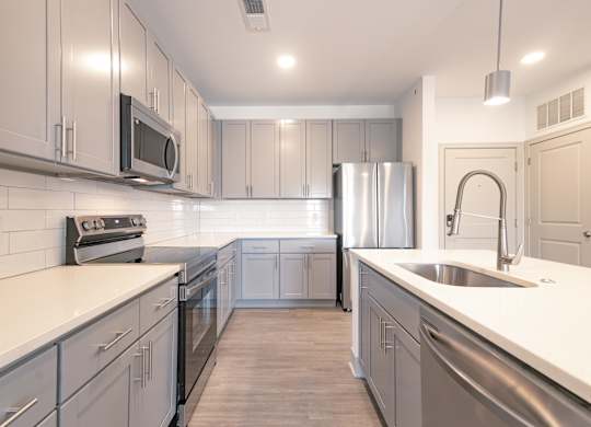 an empty kitchen with stainless steel appliances and white counter tops