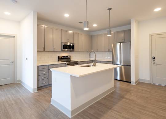 a kitchen with an island and a stainless steel refrigerator