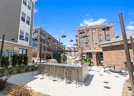a patio with a bar and chairs in front of a building