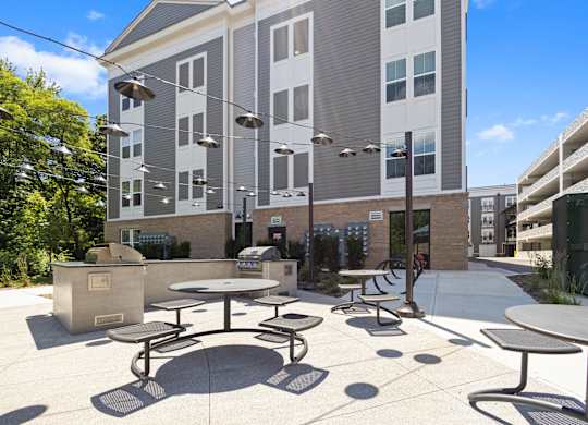 a patio with tables and chairs in front of an apartment building