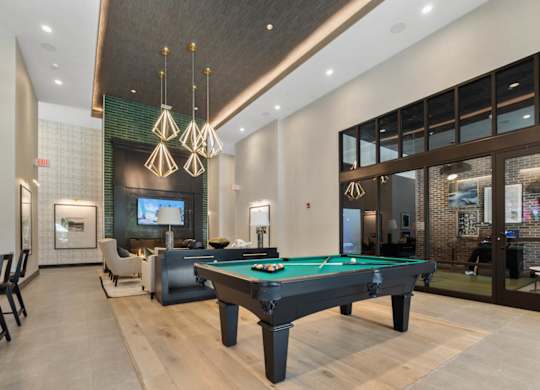 a pool table in the lobby of a clubhouse with a tv
